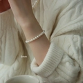 Close-up of 6mm white pearl elastic bracelet worn with a cozy knit sweater - 6mm Pearl Bracelet