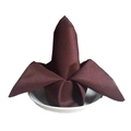 Servilleta marrón oscuro plegada en forma de flor sobre un plato de cerámica blanca - Café Oscuro