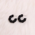 Exaggerated matte black twisted C-shape acrylic earrings on soft pink fur surface - Small Black Twisted