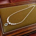 Detalle de un collar de perlas y plata con colgante de gota azul sobre terciopelo verde - Collar de Perlas de Gota de Agua