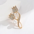 Golden tulip brooch with white crystals and a pearl on a white geometric display - Tulip Gold Pearl