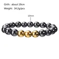 Detail of 10mm polished black magnetic beads with gold accents on an elastic bracelet - 10mm