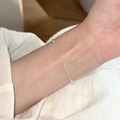 Bracelet chaîne en argent avec perles ovales en métal porté au poignet sur tissu blanc - Style de Perle Ovale (MY36041)
