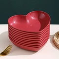 Stack of elegant red heart-shaped plastic fruit bowls with golden rim on a white table - Christmas Red-Heart Dish