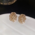Detailed macro shot of gold hollow oval earrings with sparkling white zircons on a tray - Gold