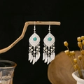 Detail of silver Bohemian tassel earrings with turquoise stones on a dark wood branch - E5775-20/Feather Shape Retro Turquoise