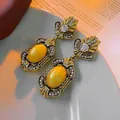 Nahaufnahme von Vintage Gold-Ohrringen mit Bernstein-Steinen auf einer Buchseite - Roter Blumen-Bernstein-Steinstil (10#)