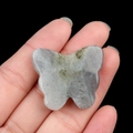Talla de mariposa de ágata gris con patrones naturales sostenida en la mano sobre fondo negro - Labradorita / 30*35mm Sin Agujero