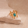 Détail d'une bague dorée texturée avec zircon bleu ovale sur un support en pierre - Clôture de Piquet d'Or