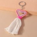 Dettaglio di nappe a cuore fatte a mano in rosa e viola su un portachiavi in metallo - Rosa