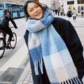 Woman wearing a thick blue and white checkered scarf with tassels in a city street - Deep Blue Yellow