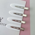 Close-up of four creamy white seamless hair clips for makeup and styling with metal base - White