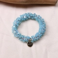 Detail view of light blue beaded elastic hair tie bracelet with a gold Morava metal tag - Jelly Blue