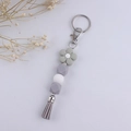 Detail of grey silicone floral keychain with beaded strap and leather tassel accent - Gray
