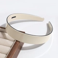 Close-up of beige wide headband with black piping on a wooden display stand - Wide Version / Beige