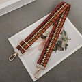 Close-up of woven geometric bag strap with vintage gold metal hooks and adjustable buckle - Orange Black Red + Gold Hook