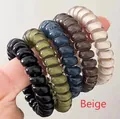 Close-up of flexible spiral hair ties in black, olive, navy, coffee, and beige colors - Beige