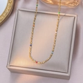Elegant rainbow bead and gold titanium steel necklace on champagne jewelry pad - Necklace / Gold
