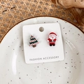 Gros plan de boucles d'oreilles asymétriques Père Noël et sapin sur un plat blanc - H Sapin de Noël + Père Noël en rouge