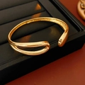 Detailed macro view of 18K gold plated teardrop open bangle with polished dual-line design - Gold