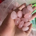 Polished natural pink rose quartz heart stones being poured from a small clear plastic bag - Rose Quartz
