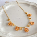Close-up van gouden sterhangers met koraalschelp en zirkoon op een wit bord - Ketting - Goud - Roze (Stijl 3)