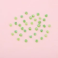 DIY green flower glass beads scattered on pink background for jewelry making - Grass Green