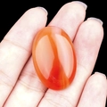 Handheld oval red agate carnelian cabochon stone with natural banded textures - Red Agate