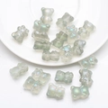 Macro view of pearlescent grey 3D bear charms scattered on a white ceramic plate - Frosted Spring Green