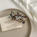 Detail of a large marble pattern acetate hair claw clip resting on a ceramic plate - Mixed Tortoise Shell