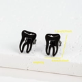 Macro view of black tooth shaped stainless steel earrings with 1.3cm x 0.9cm dimensions - Tooth / Black