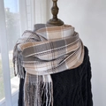 Sciarpa invernale a quadri marrone e beige con nappe su un maglione di maglia nera - caffè