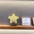 Detail of yellow star-shaped quilted crossbody bag with glossy finish on wooden shelf - Yellow