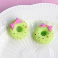 Detail of matte green resin donut charms with pink bows on a decorative ceramic plate - Small Bow - Green Base + Rose Red