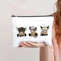 Handheld view of a canvas makeup bag with three cute cartoon highland cow illustrations - Cartoon Highland Cow Family (137-3)