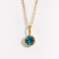Close-up of golden necklace with circular blue gemstone pendant on white background - December Blue Topaz
