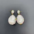 Dettaglio macro di orecchini con perle barocche e strass colorati su montatura dorata - Orecchini a Bottone con Strass Multicolore