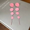 Pendientes largos rosados con textura y agujas de acero sobre un libro gris decorativo - Rosa