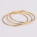 Dreiteiliges Set eleganter goldfarbener Edelstahlarmreifen mit glattem, poliertem Finish - Gold