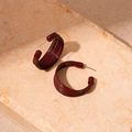 Macro detail of wine red C-shaped multilayered brushed earrings on marble stone - Dark Red