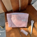 Neceser rosa de tela de burbujas con logo H & R sobre una silla de madera - Rosa