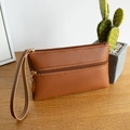Brown dual-zipper PU leather wristlet pouch with gold hardware on wooden table - Brown