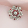 Rotating snowflake brooch with red crystals and silver metal on pink surface - Silver and Red Snowflake Brooch