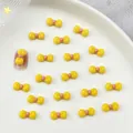 Cute yellow resin bow tie nail art charm with pink center for DIY manicure designs - Yellow