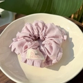 Pink striped fabric scrunchie with a logo label and rhinestone on an off-white ceramic plate - Twill Pleated Scrunchie / Strawberry Pink