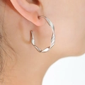 Detail of twisted silver C-shape earring worn by model showing texture and metallic luster - 18K Gold / Steel