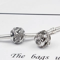 Detailed macro view of silver hollow woven charms set with rhinestones on a snake chain - Hollow Sphere