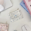 Close-up of floral fabric card holder featuring a zipper and a heart-shaped button detail - White