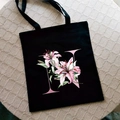 Black canvas tote bag with pink watercolor lily flower and letter N printed on front - Letter N / Black