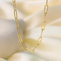 Macro detail of golden paperclip chain necklace on soft white pleated fabric background - H201 Cross Link Gold Necklace